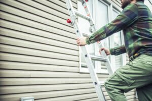 Repairman climbing the ladder to inspect the house Siding Contractor project by U.S. Windows & Exteriors for a residential home in Acworth, GA