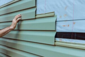 Contractor installing vinyl siding plastic panels on facade wall of new home Home exterior siding project completed by U.S. Windows & Exteriors in Brookhaven, GA